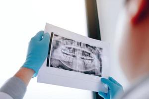 asiatische männliche zahnärzte analysieren röntgenbilder von patienten im labor. foto