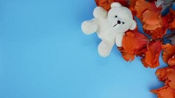 orange Hibiskusblüte und Teddybär auf blauem Hintergrund mit Kopierraum. romantisches Konzept, Grußkarte. Platz für Text. foto