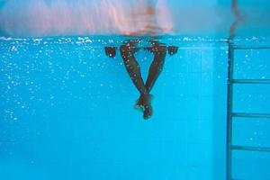 Die Beine eines erwachsenen afroamerikanischen Mannes unter Wasser im Schwimmbad foto