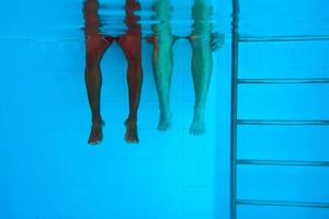 Beine eines erwachsenen afroamerikanischen Mannes und kaukasische Frauenbeine unter Wasser im Schwimmbad. sport-, erholungs-, urlaubs- und freundschaftskonzept foto