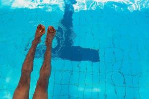 Die Beine eines erwachsenen afroamerikanischen Mannes unter Wasser im Schwimmbad foto