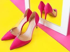 stylische rosa High Heels Schuhe auf rosa Hintergrund, die ihre eigene Reflexion im Spiegel beobachten. schuhe, mode, ego, egoistisch, narzissmus, stil, einkaufen, verkaufskonzept foto