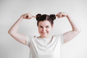 schöne frau mit zöpfen und einem lustigen gesicht, das ein t-shirt auf einem weißen hintergrund trägt. kopieren, leerer raum foto