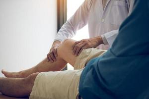 Physiotherapeuten verwenden den Griff am Knie des Patienten, um auf Schmerzen zu prüfen. foto