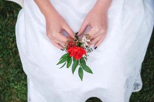 Boutonniere für die Hochzeit in den Händen einer Mädchenbraut in einem weißen Kleid. kopieren, leerer platz für text foto