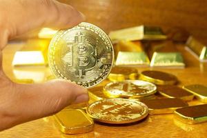 die hand des mannes nimmt bitcoin goldenes geld auf, das auf den holzboden gelegt wurde. Szene mit Goldbarren verzieren. sie dienen zum Tausch oder Handel und sind ein wertvoller Schatz im Anlagegeschäft. foto