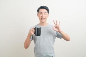 junger asiatischer mann, der kaffeetasse hält foto