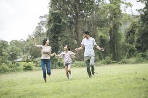 glückliche familie hat spaß mutter, vater und tochter laufen im park. foto