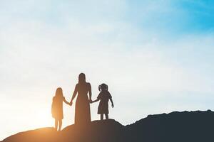 Silhouette der Mutter mit ihrer stehenden Tochter und Sonnenuntergang foto