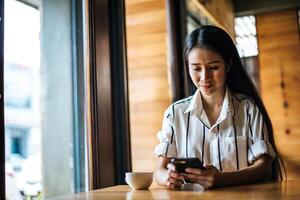 Frau sitzt und spielt ihr Smartphone im Café foto