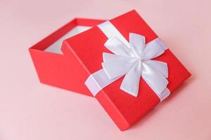 weihnachten neujahr geburtstag valentinstag feier vorhanden romantisches konzept. einfach minimalistisches Design rote Geschenkbox isoliert auf pastellrosa farbigem Hintergrund. Flache Ansicht von oben, Kopierbereich foto