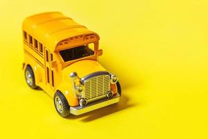 entwerfen Sie einfach den gelben klassischen Spielzeugauto-Schulbus, der auf gelbem buntem Hintergrund lokalisiert wird. sicherer täglicher Transport für Kinder. zurück zum schulkonzept. bildungssymbol, kopierraum foto
