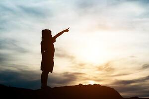 Silhouette eines kleinen Mädchens, das die Hand zur glücklichen Zeit der Freiheit hebt foto