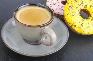 Tasse Espresso mit frischem Gebäck zum Frühstück auf schwarzem Steinhintergrund. foto