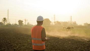 Männlicher Ingenieur, der Drohnen kontrolliert, die Düngemittel und Pestizide über Ackerland sprühen, High-Tech-Innovationen und intelligente Landwirtschaft foto