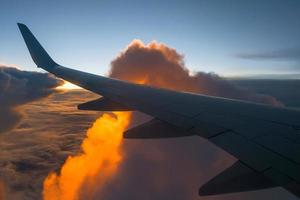 flügel des flugzeugs auf sonnenuntergangshintergrund und -wolke foto