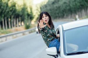 Frau, die ihren Körper durch das Fenster des Autos späht foto