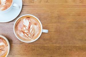 Latte-Kaffeetasse mit Kopienraum auf Holzschreibtisch foto