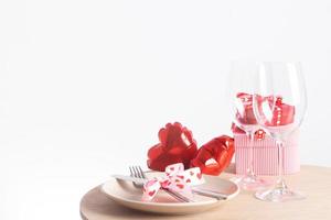 Servieren für ein romantisches Abendessen am Valentinstag - Besteck und Weingläser mit Teller und roten herzförmigen Luftballons auf dem Tisch mit Kopierraum foto