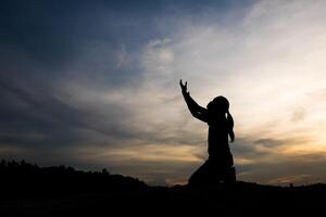 Silhouette einer Frau, die mit Gott betet foto