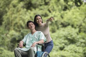 Behinderter Mann im Rollstuhl und Freundin im Park foto