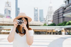 asiatische Frau des glücklichen schönen Reisenden tragen Rucksack. junge fröhliche asiatische frauen, die kamera benutzen, um während der stadtrundfahrt fotos zu machen, fröhliche emotionen, tolle stimmung. frauen lebensstil im freien im stadtkonzept.