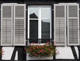 klassische elsässische fenster in einem fachwerkhaus, verziert mit holzschnitzereien und blumen foto