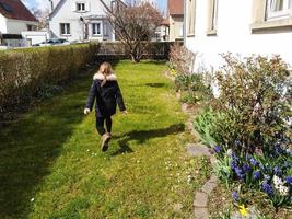 kleines Mädchen, das im blühenden Garten läuft, Frühlingszeit foto