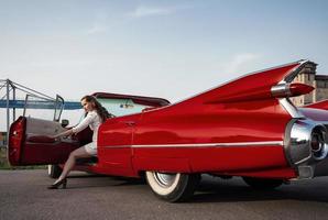 60er Jahre Oldtimer roter Cadillac und ein wunderschönes junges Mädchen foto