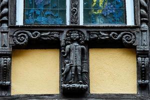 klassische elsässische fenster in einem fachwerkhaus, verziert mit holzschnitzereien und blumen foto