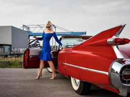 60er Jahre Oldtimer roter Cadillac und ein wunderschönes junges Mädchen foto