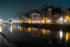 Ile River Damm in Straßburg bei Nacht, Nebel. Reflexionen von beleuchteten Gebäuden und Laternen im Wasser foto