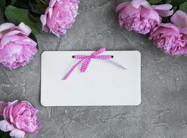einladungskarte und rosa pfingstrosenblumen foto