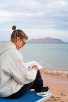 junge künstlerin malt oder macht reiseskizzen mit aquarell am meer foto