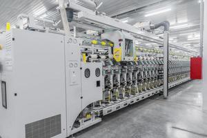 Maschinen und Geräte in der Werkstatt zur Herstellung von Garn. Innenraum der industriellen Textilfabrik foto