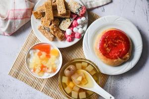 chinesische desserts chinesisches gebäck bohnenkuchen, snack mischung nüsse süßigkeiten zucker nüsse sesam samen beschichtete bohnen puffreis, milchpudding obstsalat longan saft schüssel im chinesischen neujahrsfest essen foto