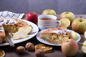 große Portion Apfelkuchen mit Walnüssen, umgeben von reifen Äpfeln. foto