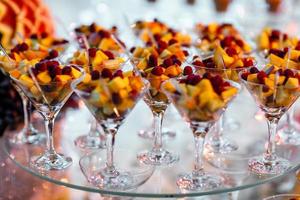Martini-Gläser mit vielen verschiedenen Früchten auf einem Glasständer. Bankett zur Feier von Geburtstag, Hochzeit. foto