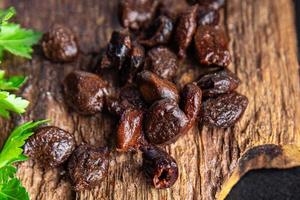 oliven schwarze entkernte getrocknete früchte geräucherter lebensmittelsnack auf dem tisch foto