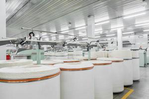 Maschinen und Geräte in der Werkstatt zur Herstellung von Garn. Innenraum der industriellen Textilfabrik foto
