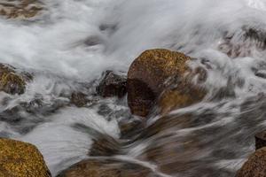 Fluss eines Bergflusses mit abgerundeten Steinen foto