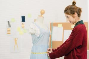 professionelle schöne asiatische Modedesignerin, die Messkleid auf einem Mannequin-Kleidungsdesign im Studio arbeitet. Lebensstil Frauen Arbeitskonzept. foto