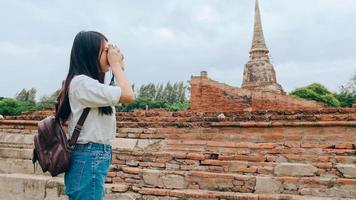 reisende asiatische frau, die kamera verwendet, um ein foto zu machen, während sie ihre urlaubsreise in ayutthaya, thailand, verbringt, japanische touristin genießt ihre reise zu einem erstaunlichen wahrzeichen in einer traditionellen stadt.