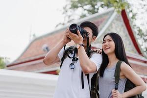 reisendes asiatisches paar, das kamera verwendet, um ein foto zu machen, während es urlaubsreise in bangkok, thailand, verbringt, paar genießt reise an erstaunlichem wahrzeichen in der stadt. Lifestyle-Paar reisen im Stadtkonzept.