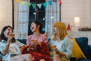 gruppe asiatischer frauen feiert zu hause, frau trinkt cocktail und redet lustig zusammen auf dem sofa im wohnzimmer in der nacht. jugendlicher junger freund spielen spiel, freundschaft, feiern urlaubskonzept. foto