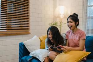 lesbisches lgbt-frauenpaar spielt spiele zu hause, asiatische frau mit joystick, die lustige glückliche momente zusammen auf dem sofa im wohnzimmer in der nacht hat. junger liebhaber fußballfan, feiern urlaubskonzept. foto