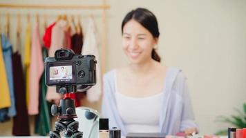 Schönheitsblogger präsentieren Schönheitskosmetik, die vor der Kamera sitzt, um Videos aufzunehmen. schöne asiatische frau verwendet kosmetik überprüfen make-up-tutorial live-videoübertragung an soziales netzwerk über das internet. foto