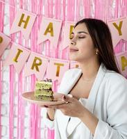 schöne aufgeregte frau, die geburtstag feiert, der kuchen macht, der wunsch hält foto