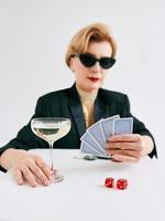 Reife stilvolle Frau im schwarzen Smoking und Sonnenbrille im Casino. glücksspiel, mode, pokerface, hobbykonzept. foto