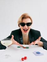 Reife, stilvolle Frau im schwarzen Smoking und Sonnenbrille freut sich, im Casino zu gewinnen. glücksspiel, mode, hobbykonzept. foto